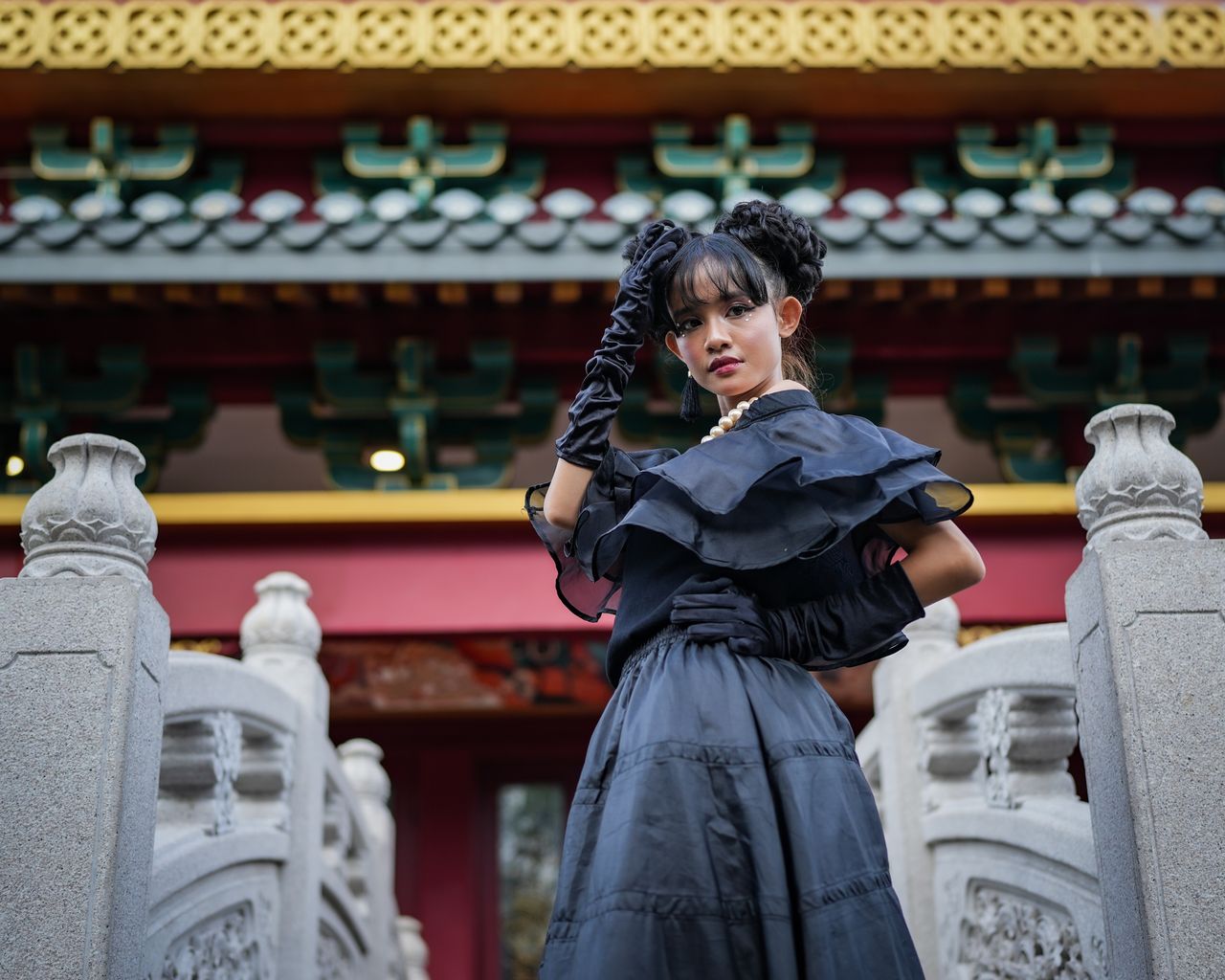 our-story A stylish woman poses in a black dress at a decorative cultural structure in Jakarta.